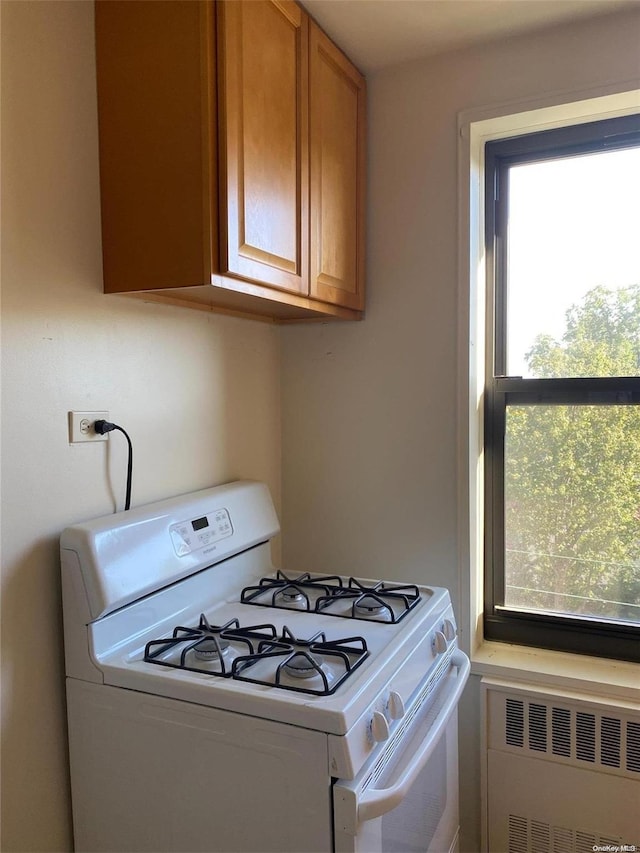 kitchen featuring white range with gas cooktop, a wealth of natural light, and radiator heating unit