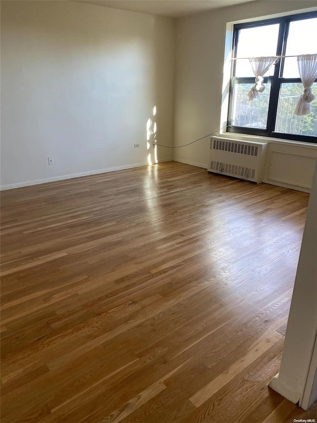 empty room with dark hardwood / wood-style floors and radiator