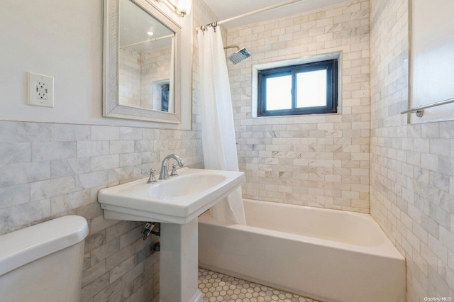 bathroom with tile patterned floors, shower / bath combo, toilet, and tile walls