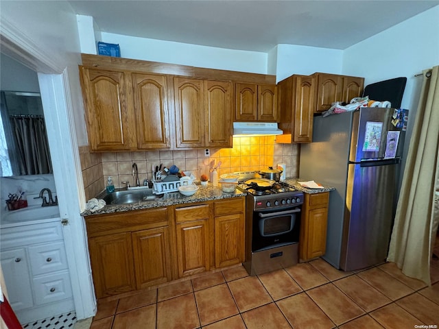 kitchen featuring stone counters, decorative backsplash, sink, and appliances with stainless steel finishes