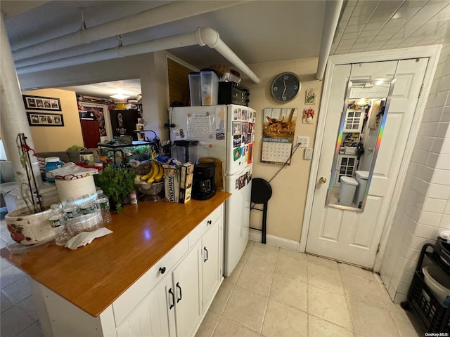 kitchen with white cabinets, white fridge, and light tile patterned floors