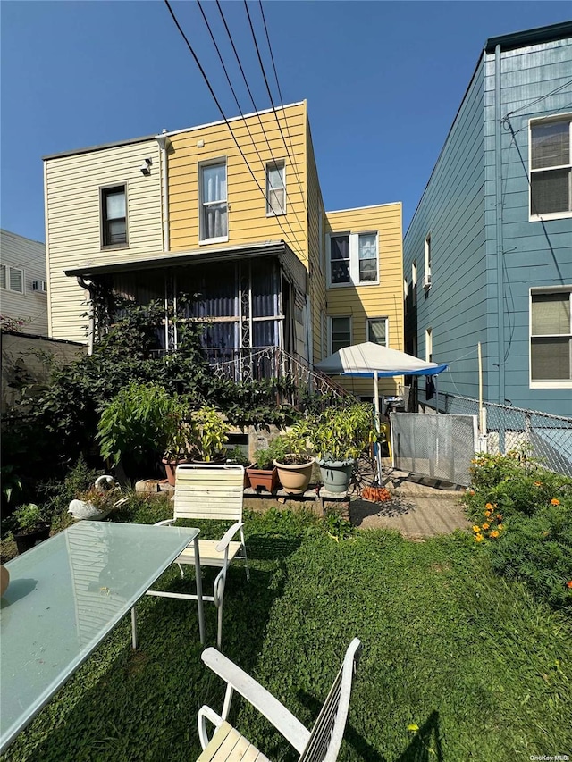 rear view of house featuring a sunroom and a lawn