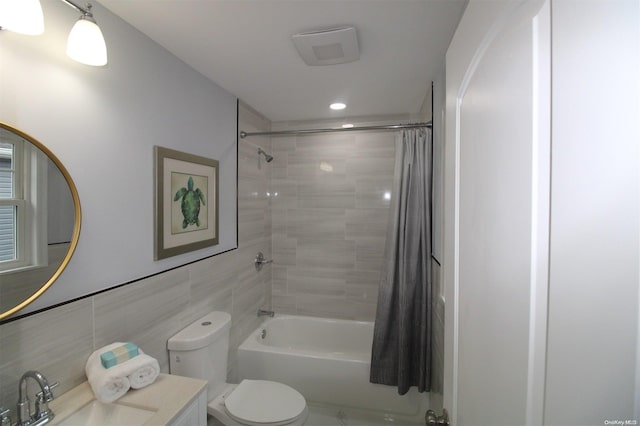 full bathroom featuring shower / bath combination with curtain, vanity, toilet, and tile walls