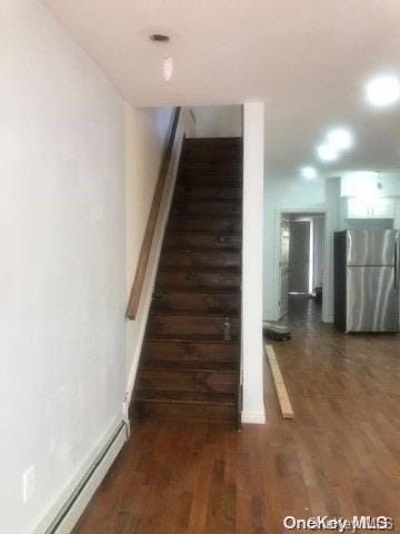 stairway featuring hardwood / wood-style floors and baseboard heating