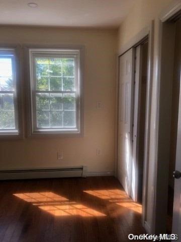 unfurnished room featuring baseboard heating and wood-type flooring