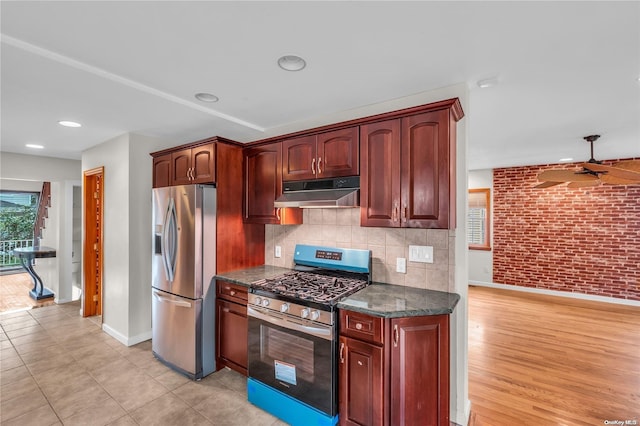 kitchen featuring brick wall, appliances with stainless steel finishes, ceiling fan, and backsplash