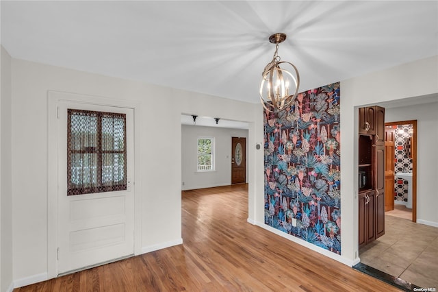 unfurnished dining area with a notable chandelier and light hardwood / wood-style floors