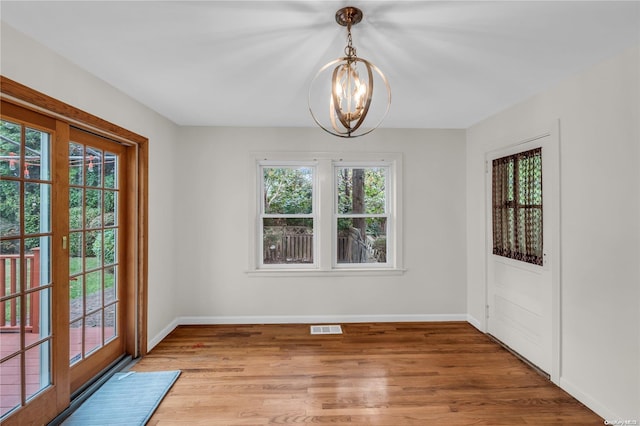 unfurnished dining area with hardwood / wood-style flooring, a chandelier, and plenty of natural light