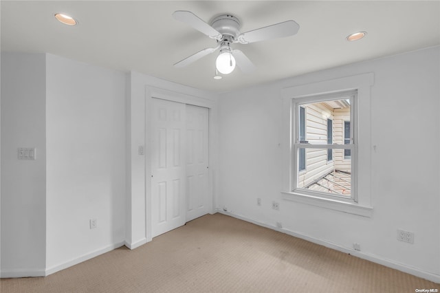 unfurnished bedroom featuring ceiling fan, a closet, and light carpet