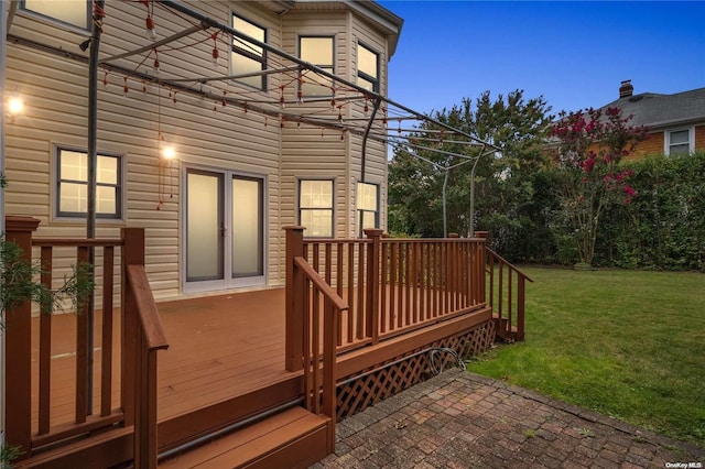 deck at dusk featuring a lawn