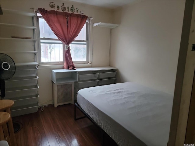 bedroom featuring radiator heating unit and dark hardwood / wood-style flooring