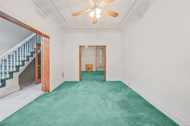 carpeted empty room with a raised ceiling, ceiling fan, and ornamental molding