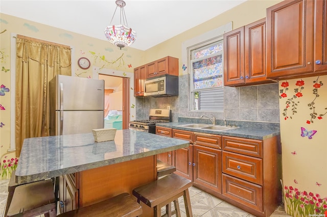 kitchen featuring sink, stainless steel appliances, pendant lighting, decorative backsplash, and a breakfast bar