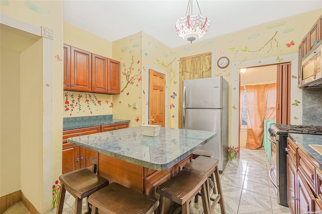 kitchen featuring a breakfast bar, stainless steel appliances, a center island, hanging light fixtures, and light tile patterned flooring