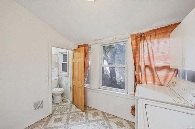 bathroom featuring tile walls and lofted ceiling