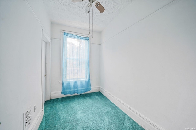 carpeted spare room featuring a textured ceiling and ceiling fan