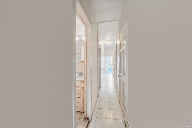 hallway featuring sink and light tile patterned flooring