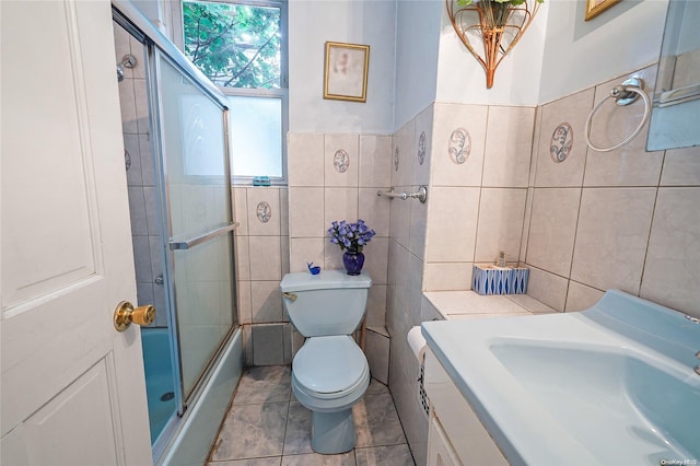 full bathroom featuring bath / shower combo with glass door, vanity, tile walls, tile patterned flooring, and toilet