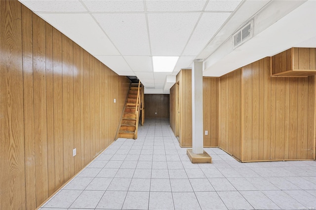 hallway featuring a paneled ceiling and wood walls