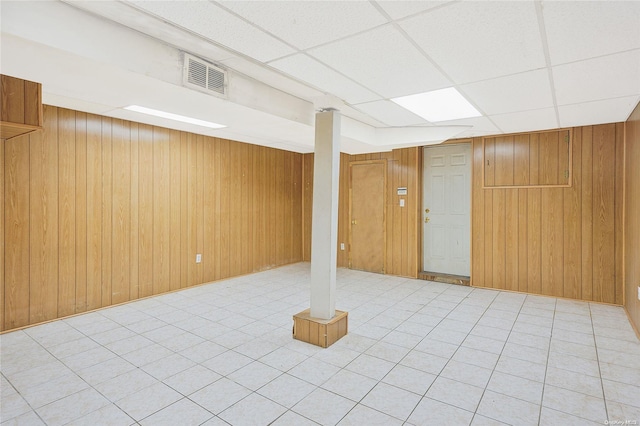 basement with a paneled ceiling and wooden walls