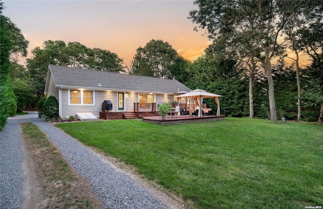 back house at dusk with a gazebo, a wooden deck, and a yard