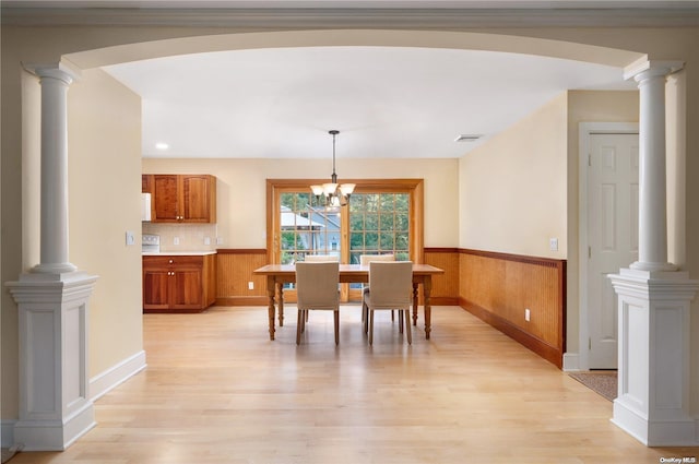 dining room with light hardwood / wood-style floors, an inviting chandelier, and wooden walls