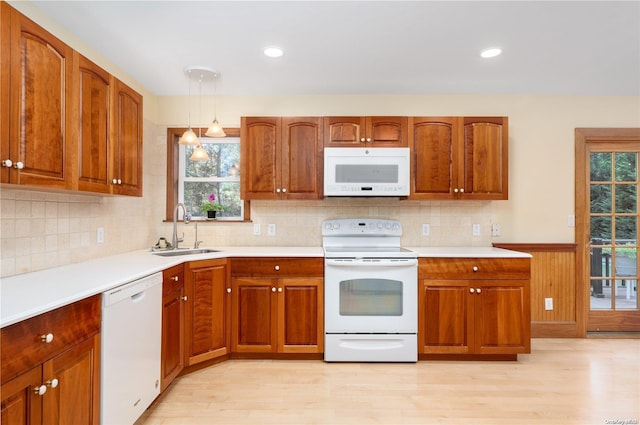 kitchen featuring sink, hanging light fixtures, tasteful backsplash, light hardwood / wood-style flooring, and white appliances