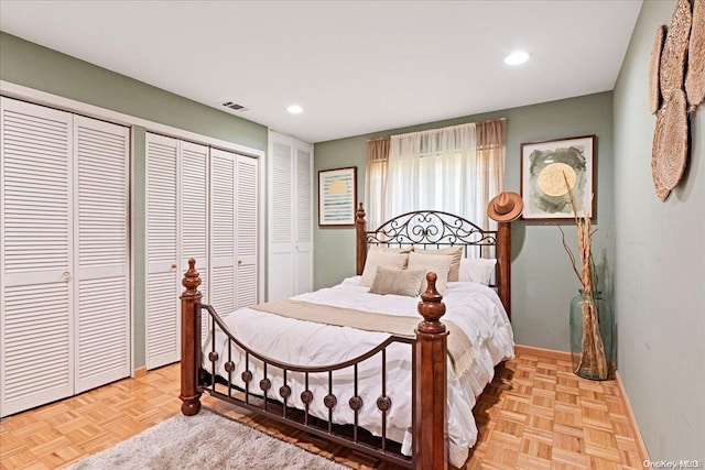 bedroom with light parquet flooring and two closets