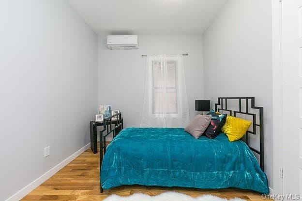 bedroom featuring an AC wall unit and wood-type flooring