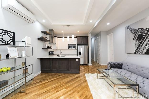 living room with light hardwood / wood-style floors, sink, and a wall mounted AC