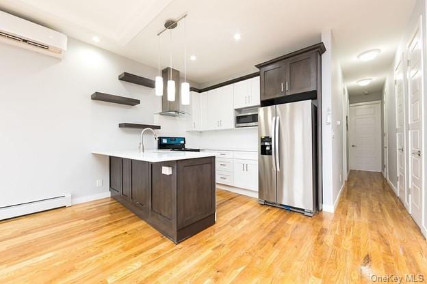 kitchen with dark brown cabinetry, wall chimney exhaust hood, hanging light fixtures, and appliances with stainless steel finishes