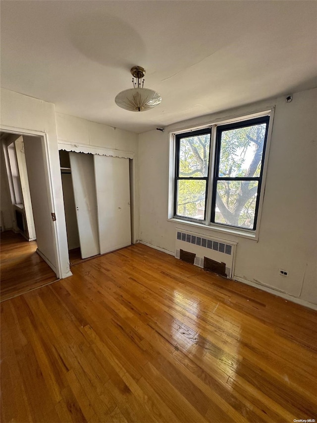 unfurnished bedroom with wood-type flooring and radiator