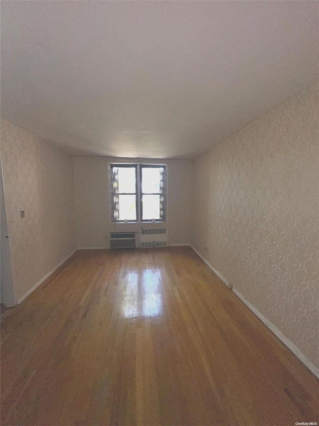 empty room with wood-type flooring and radiator heating unit