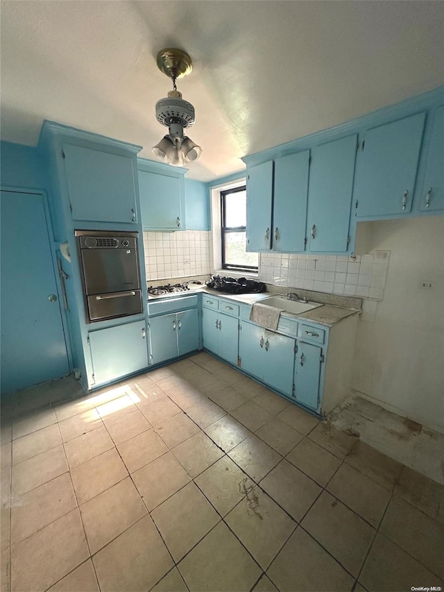 kitchen featuring blue cabinetry, backsplash, white gas stovetop, and sink