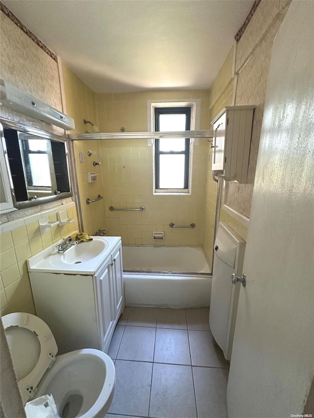 full bathroom with vanity, shower / bath combination with glass door, tile patterned floors, toilet, and tile walls