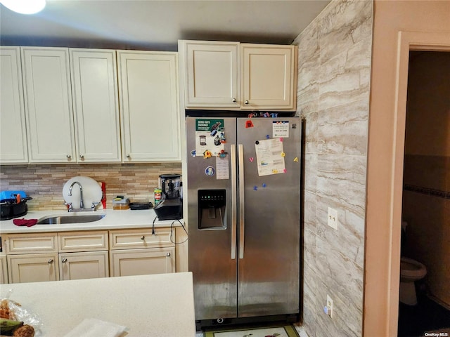 kitchen with decorative backsplash, stainless steel fridge, sink, and cream cabinets