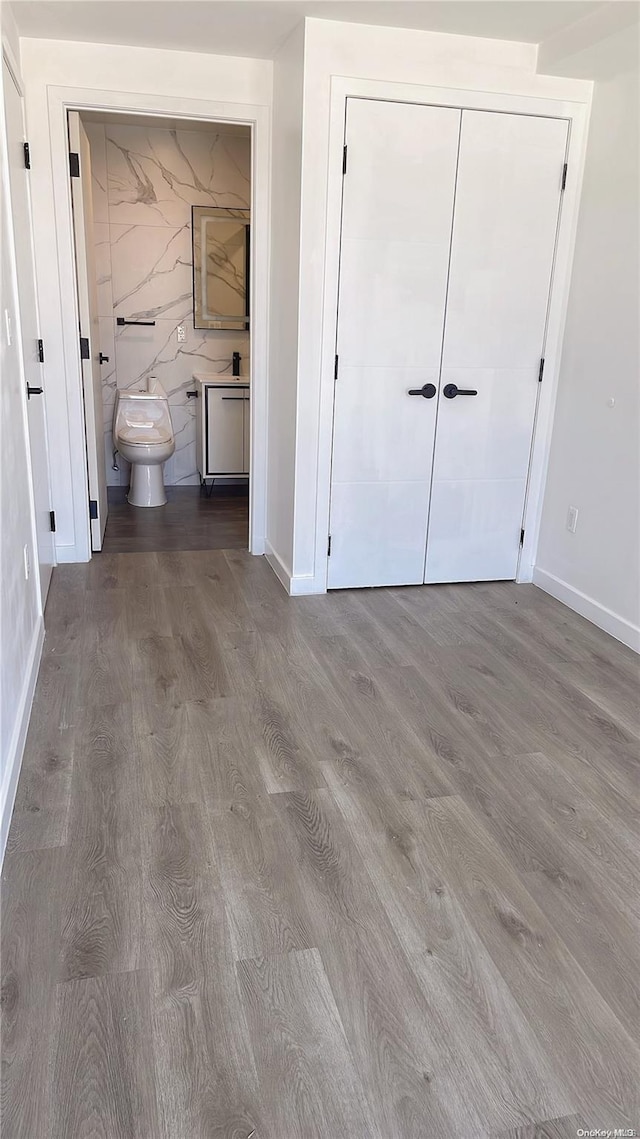 unfurnished bedroom featuring connected bathroom, a closet, and hardwood / wood-style floors