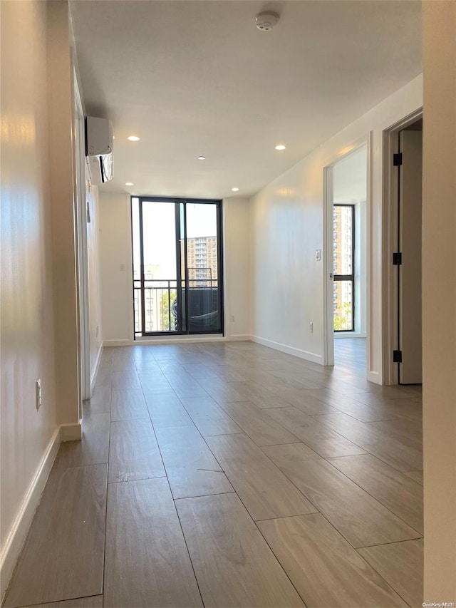 unfurnished room with an AC wall unit and light hardwood / wood-style flooring