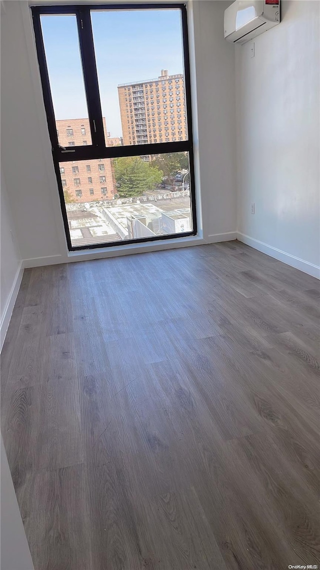 spare room with an AC wall unit and wood-type flooring