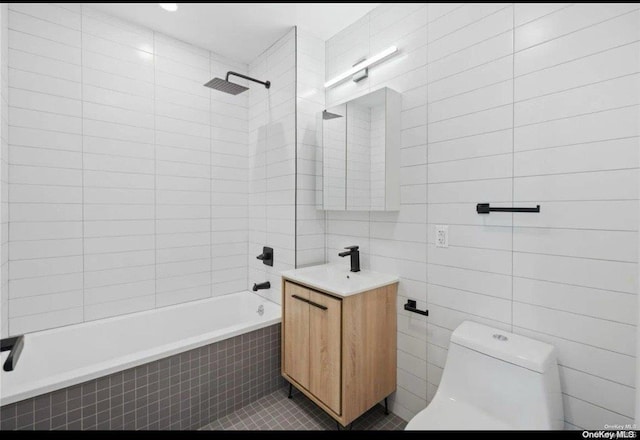 full bathroom featuring vanity, tiled shower / bath combo, toilet, and tile walls