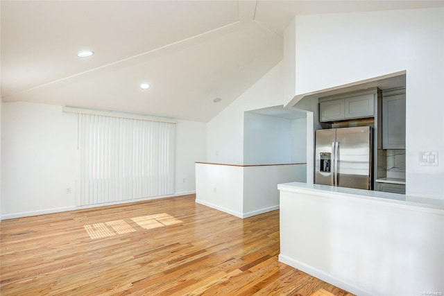 empty room with light hardwood / wood-style flooring and lofted ceiling