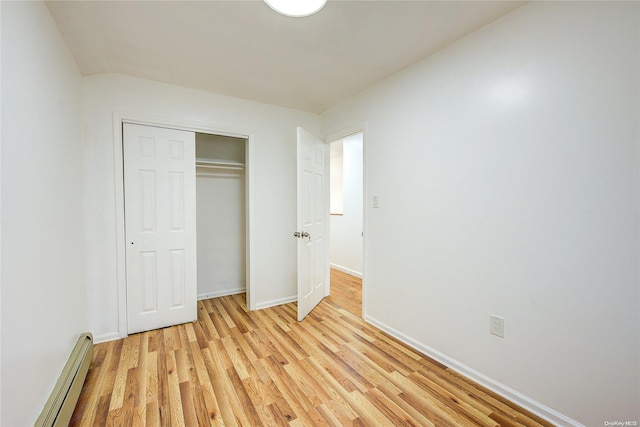 unfurnished bedroom with light wood-type flooring, a closet, and a baseboard heating unit