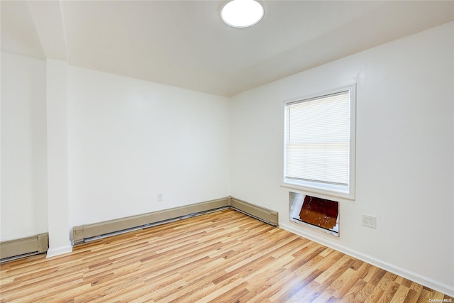 spare room featuring a baseboard heating unit and light hardwood / wood-style flooring