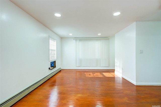 empty room featuring hardwood / wood-style flooring and a baseboard heating unit