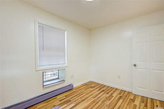 unfurnished room featuring baseboard heating and light wood-type flooring