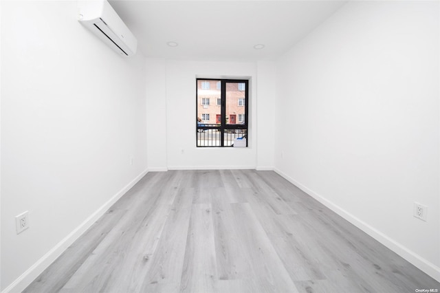 spare room featuring light hardwood / wood-style flooring and a wall unit AC