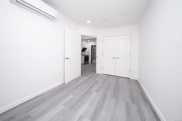 hallway with light hardwood / wood-style flooring and a wall mounted AC