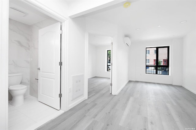 interior space with light hardwood / wood-style flooring and a wall unit AC