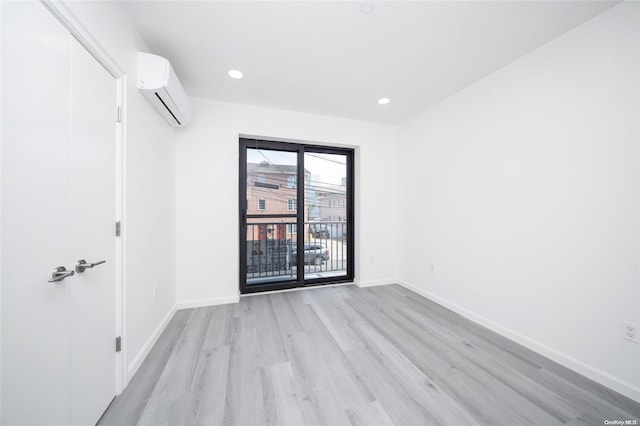 unfurnished room featuring a wall mounted air conditioner and light hardwood / wood-style floors