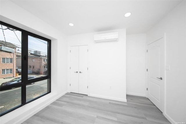 spare room with light hardwood / wood-style flooring and an AC wall unit